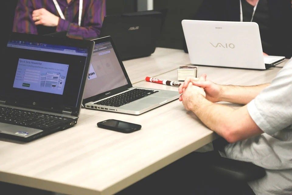 Três pessoas reunidas, cada uma com seu notebook.