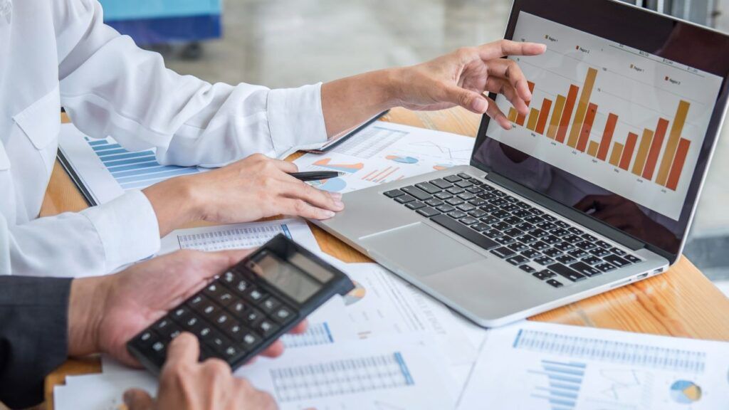 2 pessoas fazendo a análise financeira da empresa a partir de cálculos e gráficos