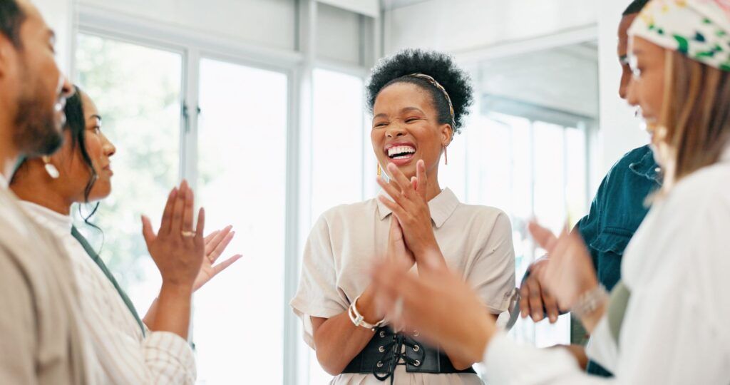 Pessoas negras na empresa, em pé, aplaudindo e sorrindo