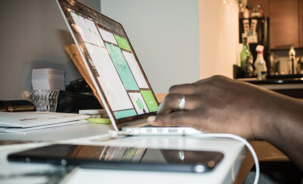 Mulher sentada em seu home office, com seu notebook, cadernos e livros.