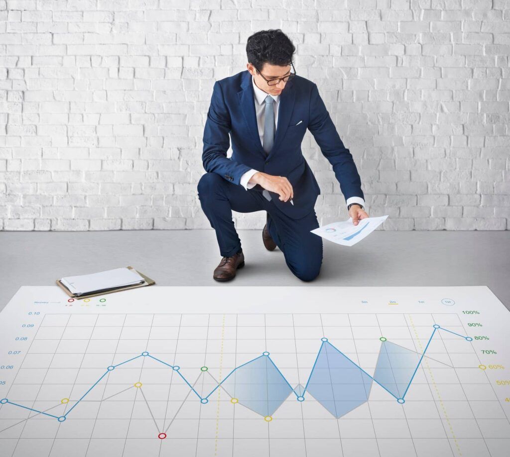 Um homem olhando para um papel para conferir um gráfico posto ao chão.
