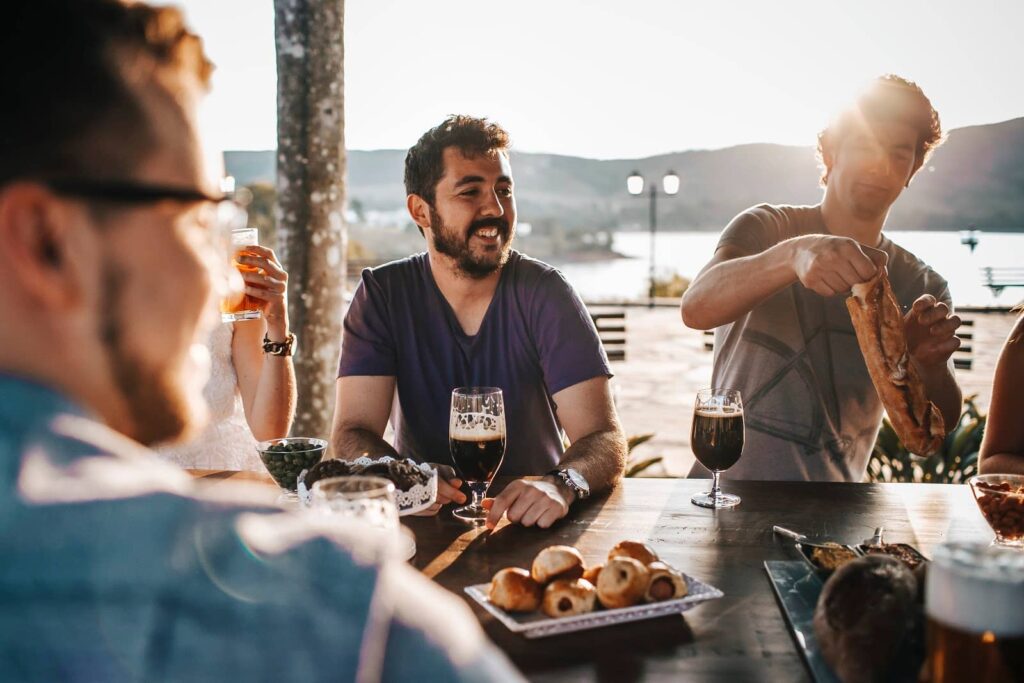 Homens em um momento de descontração, em uma confraternização corporativa externa, com drinks e snacks.