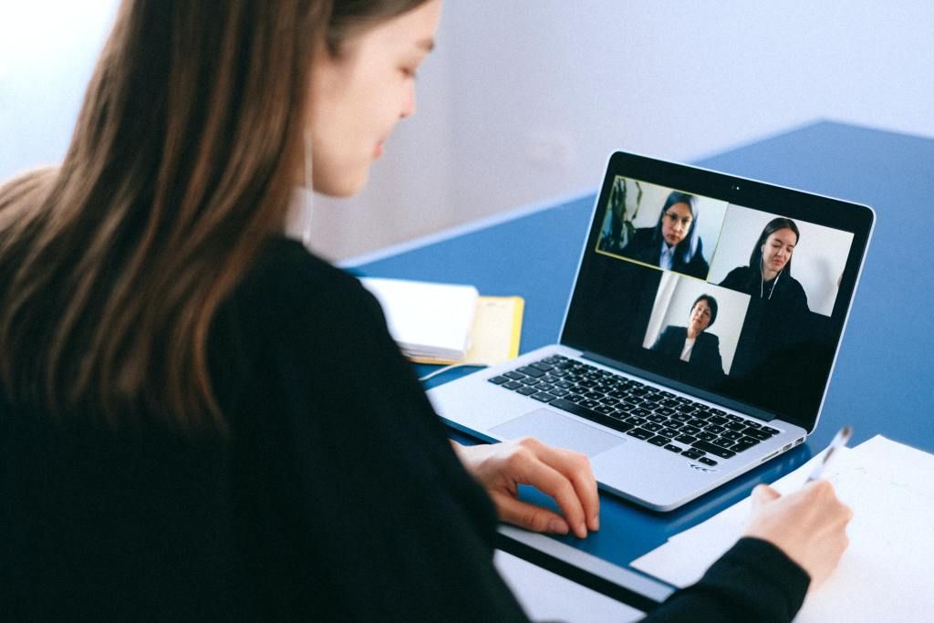 Mulher  fazendo anotações em uma dinâmica de grupo online por chamada de vídeo.