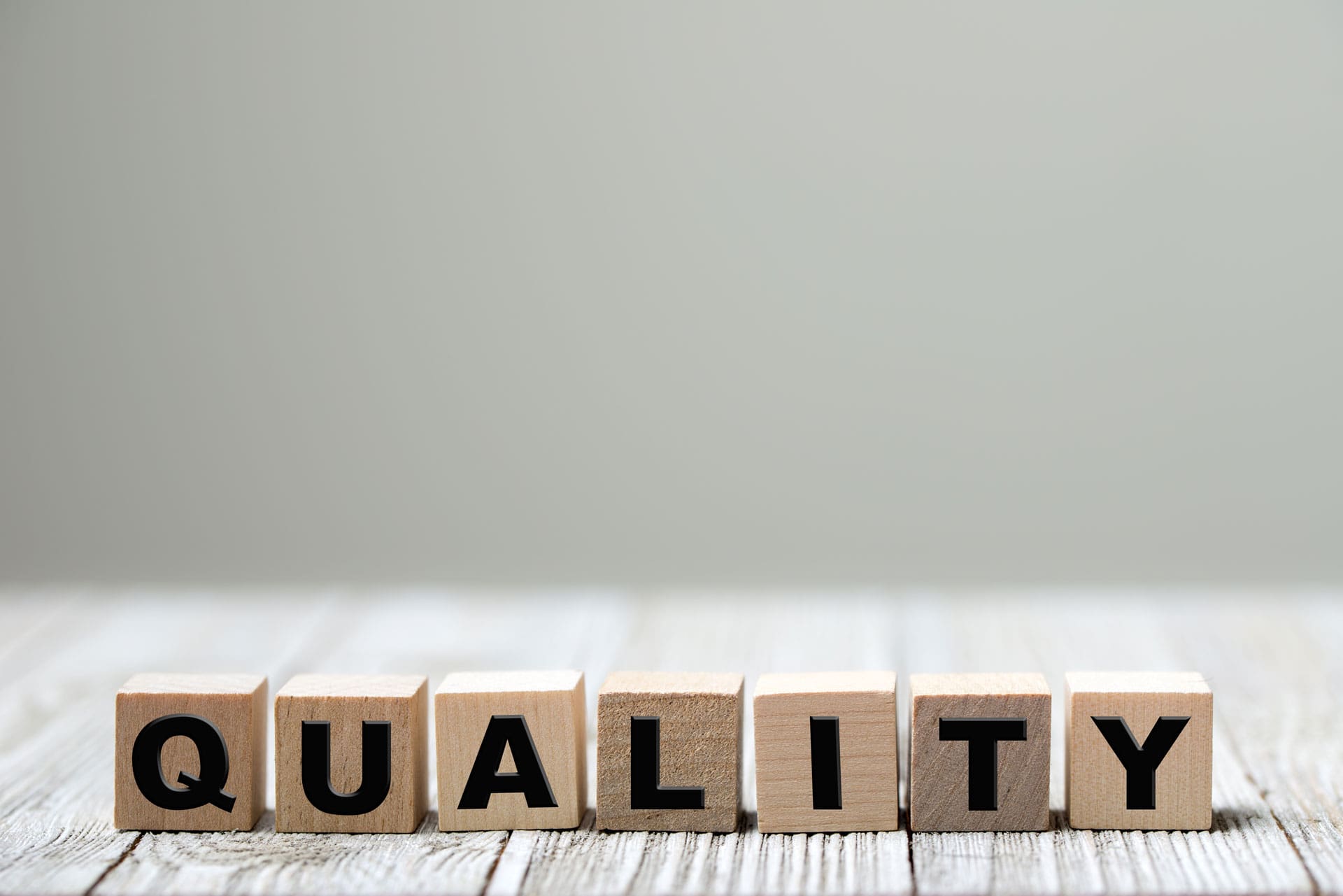 7 quadradinhos de madeira, um ao lado do outro, cada um com as respectivas letras: q, u, a, l, i, t, y