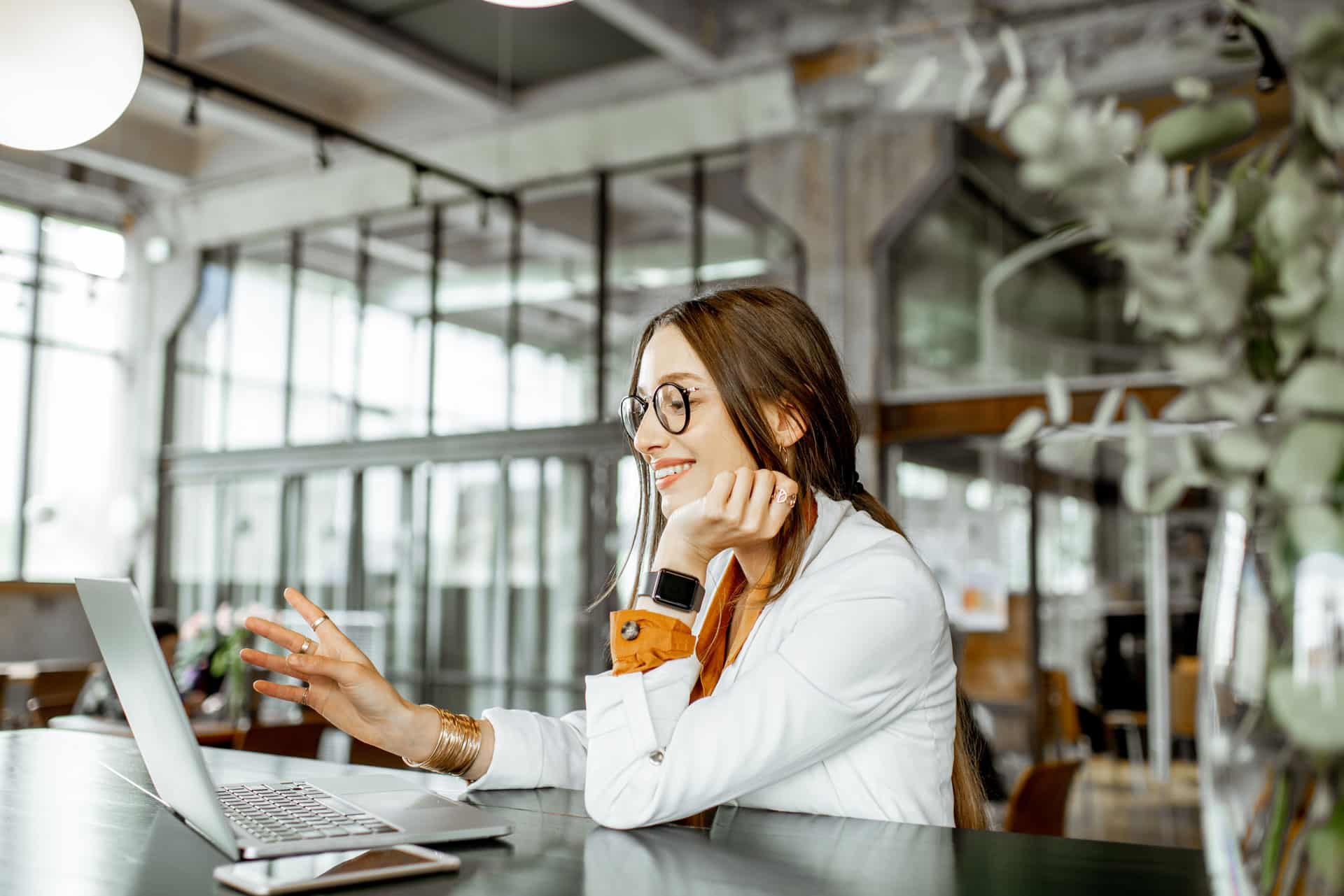 Mulher sorrindo e trabalhando em um notebook em sua casa.